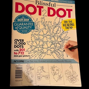 May include: A magazine cover for a dot-to-dot activity book called "Blissful Dot 2 Dot". The cover features a black and white illustration of flowers with a hand holding a pen over the page. The text "Over 11,000 Dots with 201 to 712 dots per picture" is visible. The cover also includes the text "Try the Healing Trend" and "Guarantee of Quality".