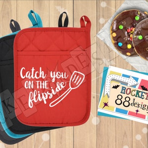 May include: Three red, black, and teal oven mitts with a white design that says "Catch you on the flipside" with a spatula graphic. The mitts are on a wood surface with a card that says "ROCKET 88designs" and two chocolate donuts with colorful sprinkles.