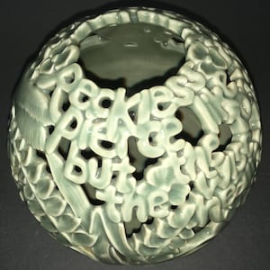 May include: A green ceramic sphere with cut-out letters spelling "Backless but they were there".