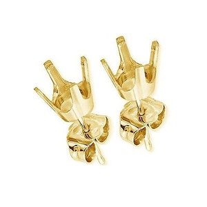 May include: A pair of gold earring settings with prongs for holding a gemstone. The settings are designed to be used with a stud earring post.