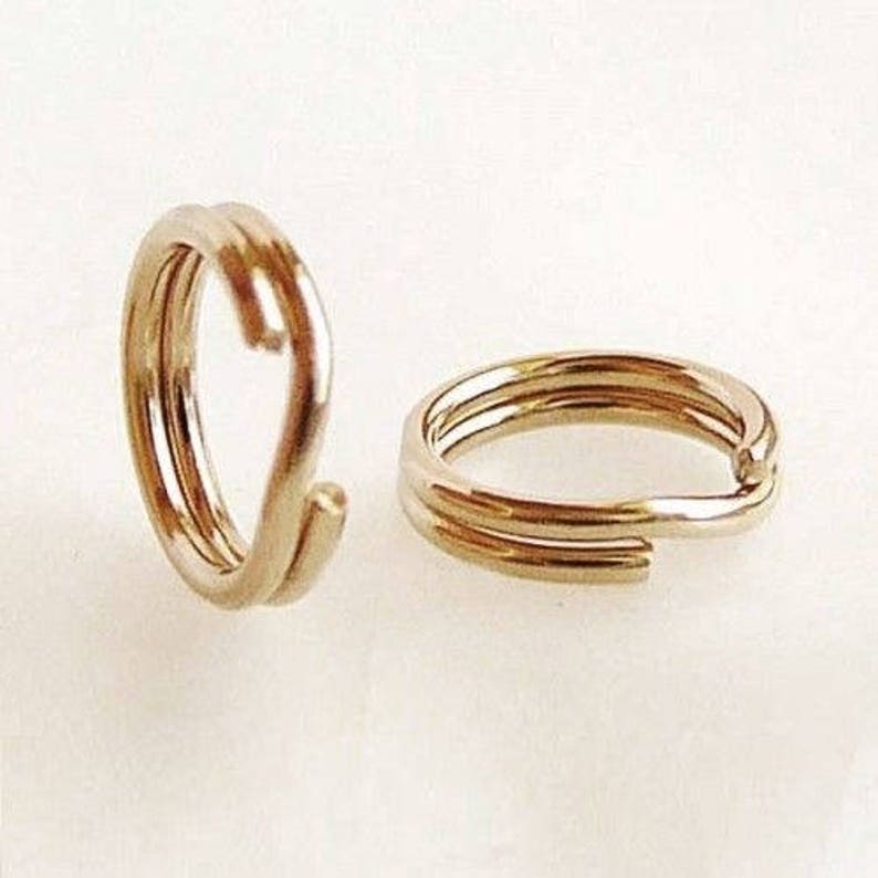 May include: Two gold-coloured metal key rings. Each ring is made of three intertwined loops.