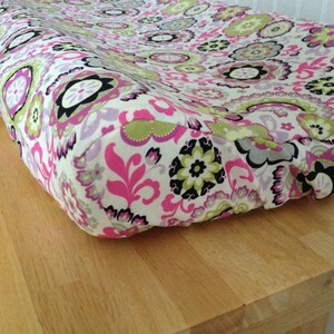 Peut inclure: Une housse de matelas à langer à motifs floraux roses, verts et blancs.