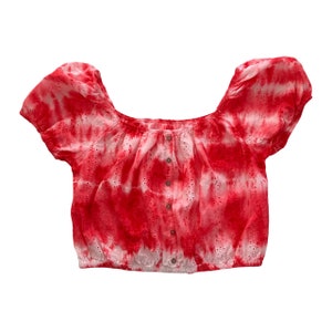 May include: Red and white tie-dye off-the-shoulder crop top with eyelet detailing and a button closure.