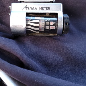 以下が含まれることがあります： ASA 800 と表示され、10 から 18 までの範囲を持つダイヤルが付いた銀と黒のエアーズメーター。メーターには、Amp と表示されるダイヤルもあります。