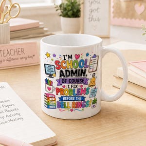 以下が含まれることがあります： カラフルな文字で「I'M SCHOOL ADMIN, OF COURSE I FIX PROBLEMS BEFORE THE BELL RINGS!」と書かれた白いセラミックマグ。マグには大きなハンドルがあり、学校をテーマにしたグラフィックで装飾されています。