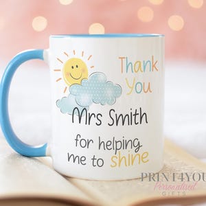 May include: White ceramic mug with a blue handle and rim. The mug features a smiling sun, cloud, and the text "Thank You Mrs Smith for helping me to shine."
