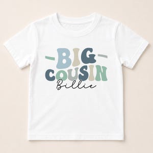 A white t-shirt with the text "BIG COUSIN Billie" printed on it.
