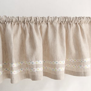Op de afbeelding: Een beige linnen valance met drie rijen kleurrijk stippenband.