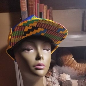 May include: A yellow, blue, green, and red patterned baseball cap with a black brim. The cap is on a mannequin head.