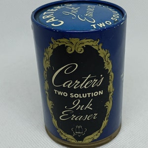 May include: A blue and gold tin container with the text "Carter's Two Solution Ink Eraser" on the front. The container is designed to hold a two-solution ink eraser.