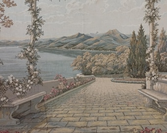 May include: Tapestry depicting a scenic landscape with a lake, mountains, and a stone pathway. The scene includes columns adorned with climbing flowers, benches, and a garden with colorful flowers. The color palette is soft, with muted greens, blues, and beige.