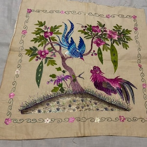 May include: A beige embroidered fabric panel featuring a blue and purple bird and a rooster perched on a tree with pink flowers. The panel is bordered with a green and white design.
