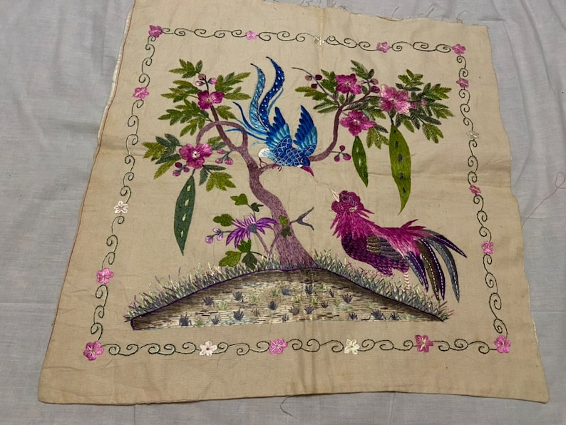 May include: A beige embroidered fabric panel featuring a blue and purple bird and a rooster perched on a tree with pink flowers. The panel is bordered with a green and white design.
