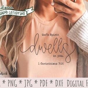 May include: A pink t-shirt with black text that reads "God's Spirit dwells in you. 1 Corinthians 3:16". The text is in a handwritten style font.