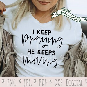 May include: White t-shirt with black text that reads "I keep praying he keeps moving".