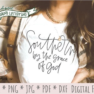 May include: A white t-shirt with the text "Southern by the grace of God" written in black cursive script. The shirt is being worn by a person with long brown hair.