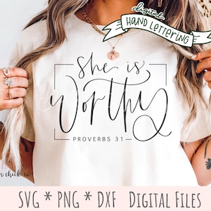 May include: A cream-colored t-shirt with the words "She is Worthy" in elegant black script, framed by a rectangular border. Below the text is "Proverbs 31." The shirt also features the text "SVG * PNG * DXF DIGITAL FILES".