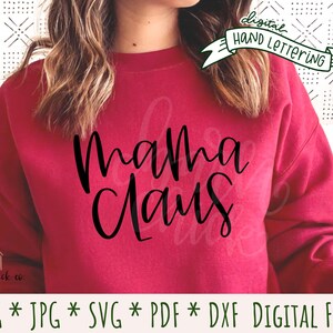 May include: A red sweatshirt with the text "Mama Claus" in black script lettering. The sweatshirt is worn by a person with long brown hair. The image includes the text "digital hand lettering" and "PNG * JPG * SVG * PDF * DXF DIGITAL FILES".