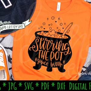 May include: A black and orange Halloween-themed graphic design featuring a cauldron with a stirring spoon, bubbles, and the text "Stirring the Pot *since birth*".
