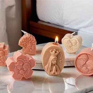 May include: Assortment of six religious themed candles, each with a different design. The candles are made of a light beige wax and feature raised images of religious figures and symbols. The candles are arranged on a white surface.
