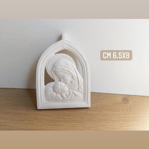 May include: A white, arched relief sculpture depicting the Virgin Mary cradling the baby Jesus. The sculpture is approximately 2.5 x 3.5 inches and features the text "CM 6.5X9".