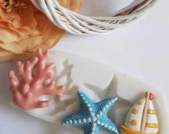 Op de afbeelding: Een siliconen mal voor het maken van taartdecoraties. De mal heeft een roze koraal, een blauwe zeester en een gele zeilboot.