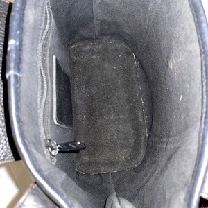 May include: The inside of a black leather tote bag with a zipped pocket and a suede lining.