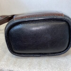 May include: A black leather handbag with a brown leather flap and a strap.