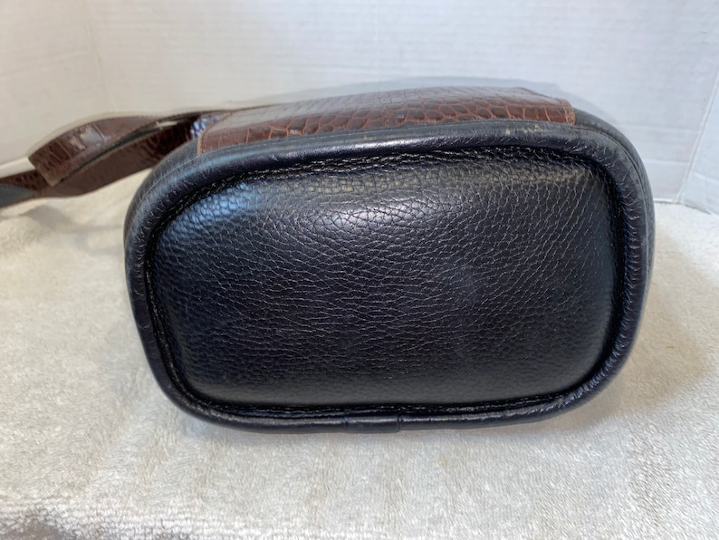 May include: A black leather handbag with a brown leather flap and a strap.