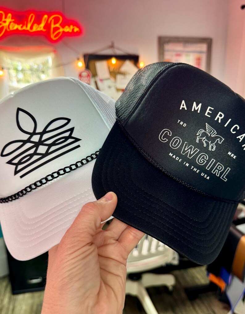White boot stitch cowgirl trucker hat styled beside black American Cowgirl cap