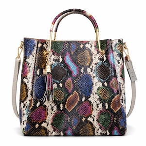 May include: A handbag featuring a multi-colored snakeskin pattern in shades of blue, green, purple, yellow, and black. It includes gold-tone metal handles, a matching tassel charm, a detachable light gray shoulder strap, and a rectangular luggage tag.