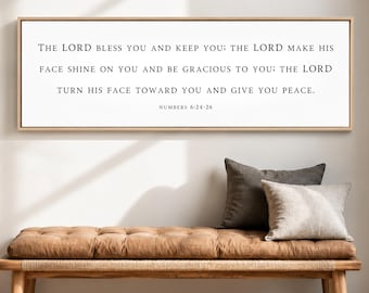May include: A rectangular wall sign with a light wood frame featuring black text on a white background that reads: THE LORD BLESS YOU AND KEEP YOU; THE LORD MAKE HIS FACE SHINE ON YOU AND BE GRACIOUS TO YOU; THE LORD TURN HIS FACE TOWARD YOU AND GIVE YOU PEACE. NUMBERS 6:24-26.