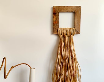 Decorative wall hanging with wooden hollow square and raffia tassel, modern creative wall sculpture, distressed wood and fiber wall art