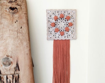 Carved wood panel with macrame berries and long fringe in terracotta color cotton rope, white washed grey square wooden wall hanging accent