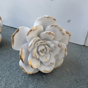 May include: White ceramic flower with gold accents. The flower has a layered, rosette design.