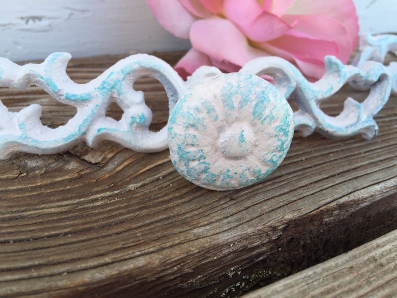 May include: White and light blue decorative knob with a distressed finish. The knob is made of metal and has a floral design.