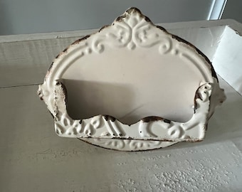 May include: White metal wall mounted decorative shelf with a scalloped edge and ornate design. The shelf has a distressed finish.