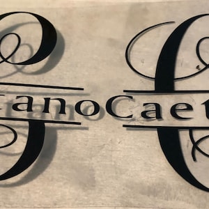 May include: Two black vinyl decals with the letter "C" in a cursive font. The letter is split in half with the name "Caetano" written in a serif font across the middle.