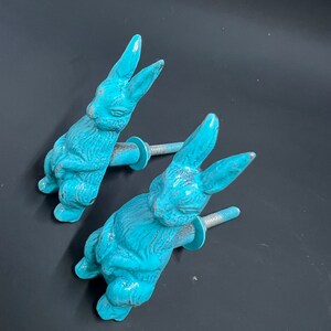 May include: Two turquoise blue rabbit shaped cabinet knobs with a silver screw.