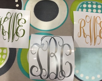 May include: Three white vinyl stickers with monogram initials. The first sticker has the initials "KWE" in green. The second sticker has the initials "SBC" in silver. The third sticker has the initials "RWE" in gold.