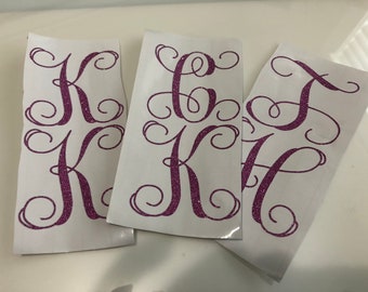 May include: Three white sheets of paper with pink glitter letters in a cursive font. The letters are K, O, and J.