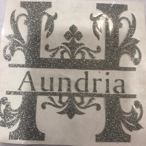 May include: A silver glitter letter H with decorative flourishes and the name "Aundria" written below it.