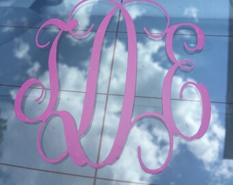 May include: Pink monogram decal featuring the letters "DE" in a cursive script font. The decal is applied to a clear glass surface.
