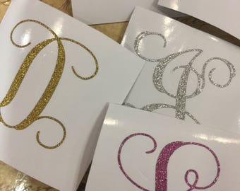May include: Five decorative letters, each with a different colour glitter finish. The letters are D, L, M, and two versions of the letter A. The letters are on a white background.