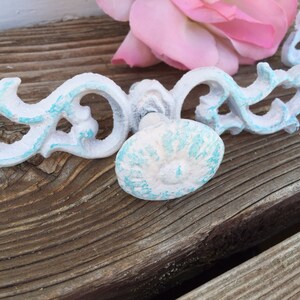 May include: White and turquoise blue decorative cabinet hardware with a floral design. The hardware is made of metal and has a distressed finish.
