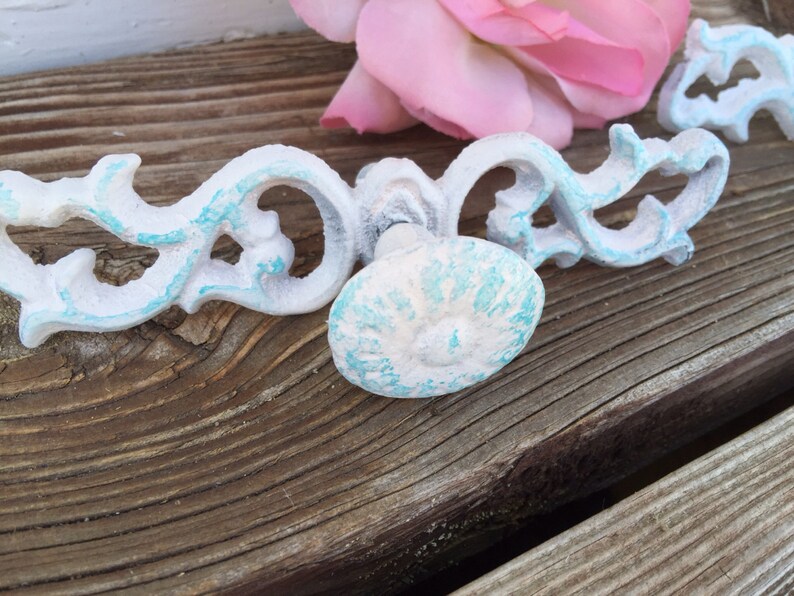 May include: White and turquoise blue decorative cabinet hardware with a floral design. The hardware is made of metal and has a distressed finish.