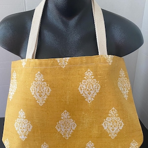 Może przedstawiać: Żółta torba typu tote z białym wzorem damaskowym. Torba ma dwa długie, kremowe paski.