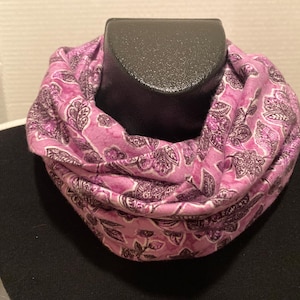 Puede incluir: Una bufanda infinita de color morado y blanco con un patrón de paisley.
