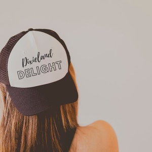 May include: A white and black trucker hat with the text "Dixieland DELIGHT" in black lettering.