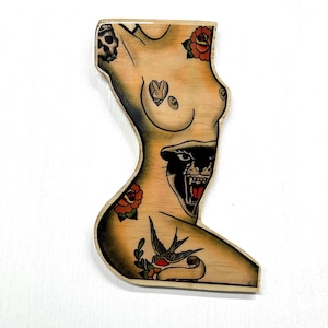 May include: Wooden cutout in the shape of a torso, featuring traditional tattoo art. The design includes a skull, roses, a panther, a swallow, and a Playboy bunny logo. The artwork is rendered in black, red, and green on a light wood background.